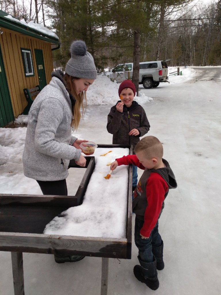 Two young children wait for maple taffy at Fortune Farms.